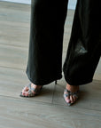 model wearing snake heels with black pants on light colored floor
