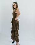 Woman wearing a brown lace dress against a white background, side view