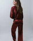 Woman wearing a burgundy satin outfit on a white background, back