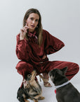 Woman in red silk outfit sitting with two dogs on a white background