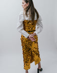 Woman wearing a gold sequin outfit on a white background back view