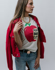 Woman wearing a graphic t-shirt with an apple design and 'New York City' text, paired with a red jacket.