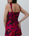 Woman wearing a red floral set with black patterns on a plain background, back