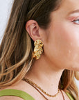 Close-up of a person wearing gold earrings and a green dress.