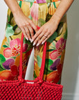 Person holding a red woven bag with a colorful floral pants and Rhodochrosite Luna Stamp Ring