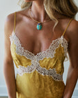 A woman wearing a yellow satin camisole with white lace trim, styled with Stone Scarab Collar Necklace