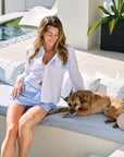 Woman sitting on a lounge chair with a dog by a poolside
