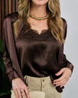 Woman wearing a brown satin blouse with lace trim and beige pants, holding a clutch, wearing Classic Necklace