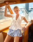 Woman in a white top and blue striped shorts on a boat