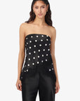 Woman wearing a black strapless top with white polka dots and black pants on a white background