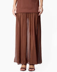 model wearing a brown dress on a white background, zoomed in on the bottom half sheer portion of the dress