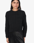 Person wearing a black sweater and pants on a white background