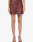 Person wearing a burgundy leather skirt on a white background