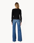 a model wearing a black cardigan with lace trim and blue jeans on a white background, back view