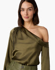 Woman wearing an olive green one-shoulder top and pants on a white background