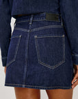Denim skirt worn by a person on a plain background, back close up