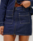 Denim jacket and skirt worn by a person on a plain background, front close up