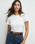 Woman wearing a white t-shirt and blue jeans against a plain background