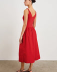 Woman wearing a red dress with cut-out back on a plain background side back view