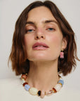 Woman wearing a colorful beaded necklace and earrings against a plain background