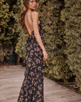 Woman in a floral dress standing in front of greenery, back view