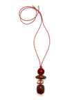 A red cord necklace featuring a stack of polished dark red and brown beads with small gold-toned spacer rings, displayed on a clean white background.