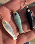 Three fish-shaped pendants on a hand