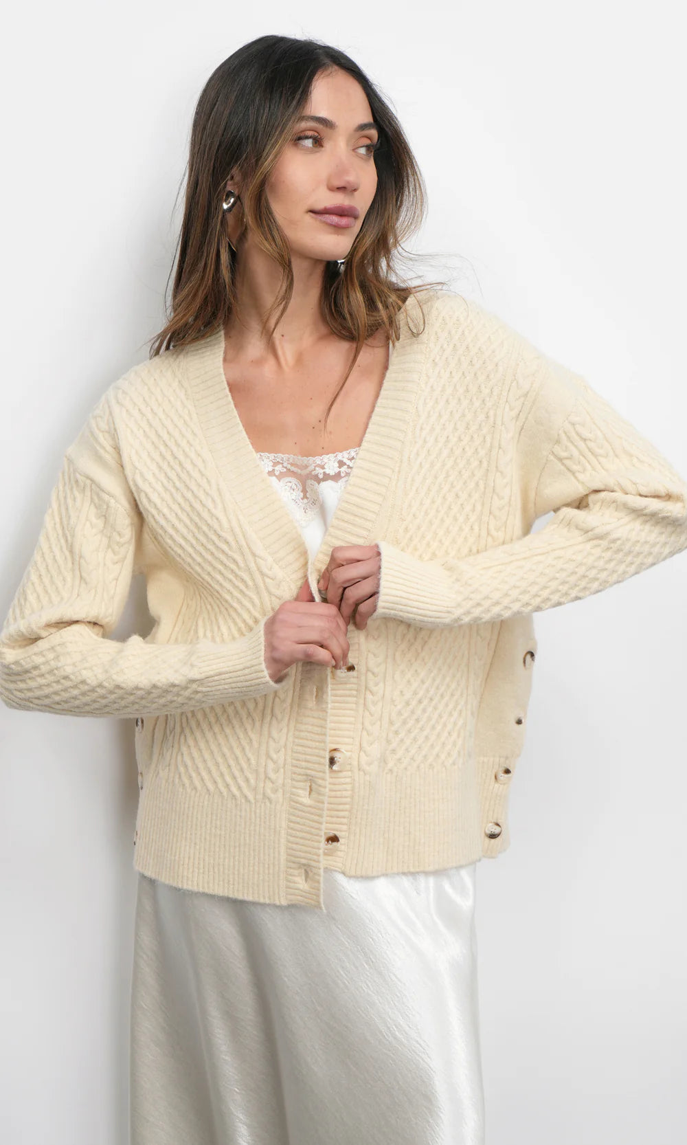 Woman wearing a cream-colored cardigan against a white background