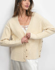 Woman wearing a cream-colored cardigan against a white background