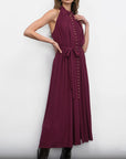 Woman wearing a burgundy dress with button details against a white background, front/side view