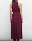 Woman wearing a burgundy halter neck dress against a white background, back view