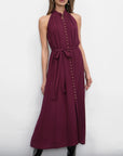 Woman wearing a burgundy dress with buttons against a white background