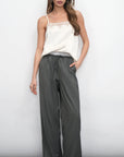 Woman wearing a white top and gray wide-leg pants against a white background