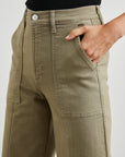 Person wearing olive green pants with a plain background