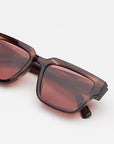 Square sunglasses with a translucent redish brown tortoiseshell frame and light red lenses, shown against a plain light gray background.