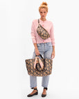 Woman holding a patterned handbag with Bandana in Khaki Blasé Eyes tied on strap