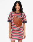 Woman wearing a striped dress with a brown bag on a white background