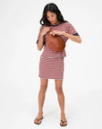 Woman wearing a striped dress holding a woven bag on a white background