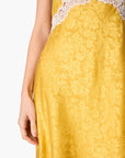 Close-up of a yellow jacquard dress with a white lace bodice trim, shown on a model against a white background.