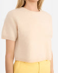 Person wearing a beige short-sleeve sweater and yellow pants on a white background