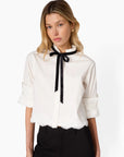 Woman wearing a white blouse with a black bow tie on a white background