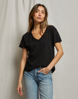 Woman wearing a black t-shirt and light blue jeans against a plain background, size S
