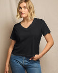 Woman wearing a black t-shirt and blue jeans against a neutral background, size L