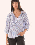 Woman wearing a blue and white striped shirt against a white background front view