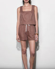 Woman wearing a brown sleeveless top and shorts set against a white background
