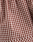 Close-up of a red and white gingham check fabric with a visible stitched hem.