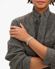 Person wearing a gray textured coat with a close-up of their arm and hand.
