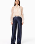 model wearing a lace tie neck long sleeve top with navy bottoms on a white background