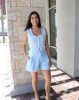 Woman in light blue outfit standing in front of a stone building.