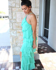 Woman wearing a green dress standing on a stone patio, side view